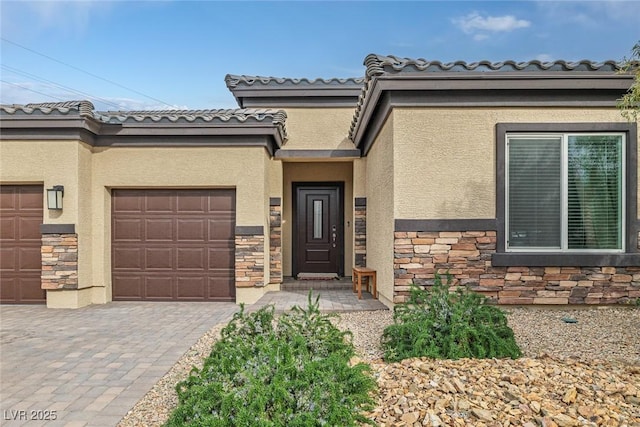 entrance to property with stucco siding, stone siding, and decorative driveway