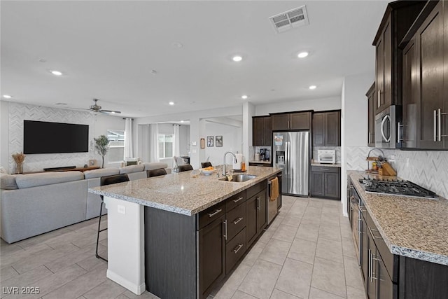 kitchen with a ceiling fan, visible vents, a sink, appliances with stainless steel finishes, and a kitchen bar