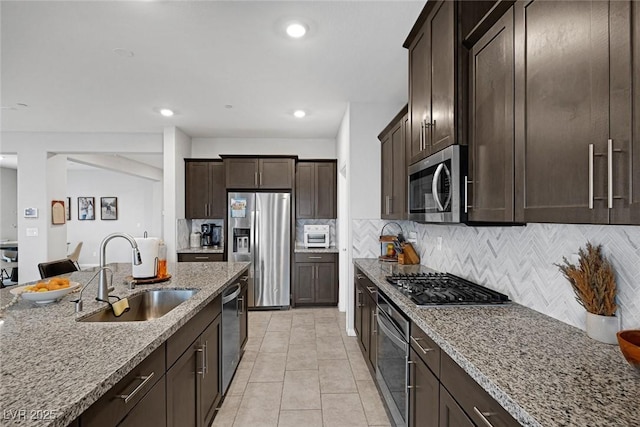 kitchen featuring a sink, dark brown cabinets, light stone countertops, and stainless steel appliances