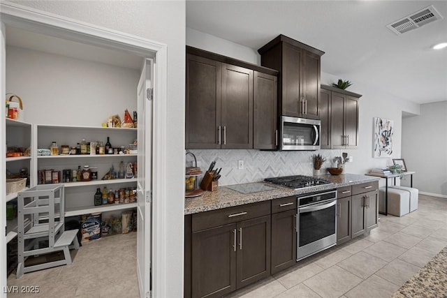 kitchen featuring visible vents, dark brown cabinets, light stone counters, decorative backsplash, and stainless steel appliances