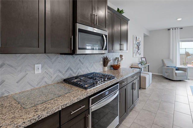 kitchen with decorative backsplash, dark brown cabinetry, light stone countertops, and stainless steel appliances