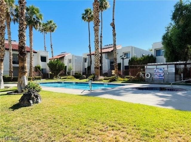 community pool with a yard, fence, and a residential view