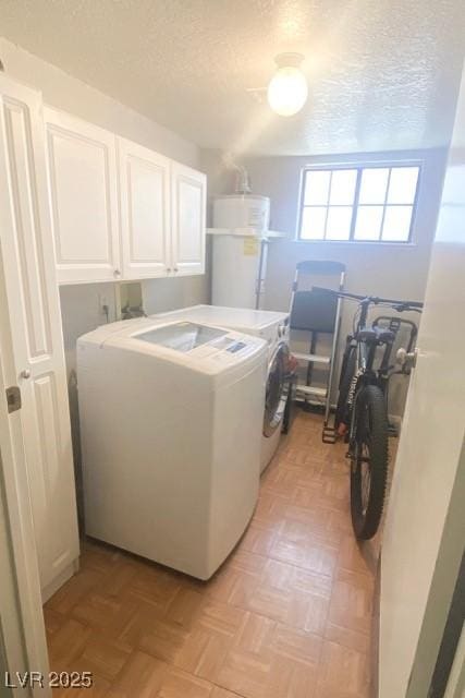 clothes washing area featuring water heater, cabinet space, a textured ceiling, and washing machine and clothes dryer