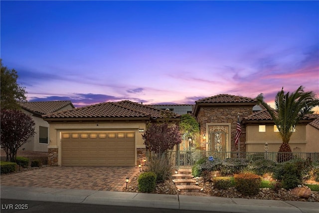 mediterranean / spanish house with stone siding, stucco siding, a tiled roof, and driveway