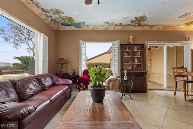 living area featuring a ceiling fan, plenty of natural light, light tile patterned flooring, and visible vents