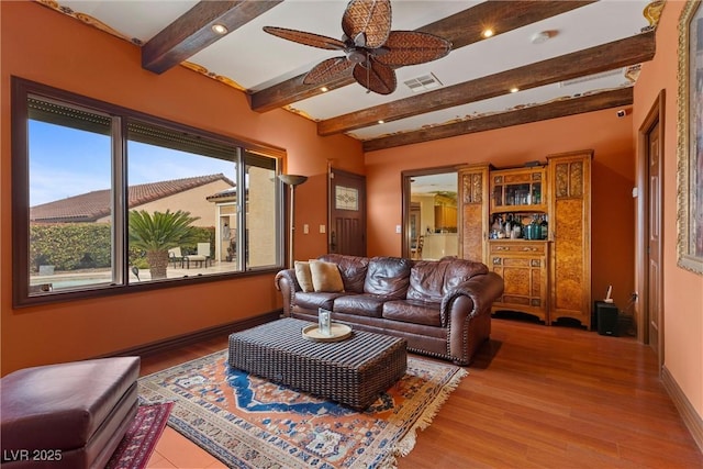 living room with visible vents, baseboards, wood finished floors, and a ceiling fan