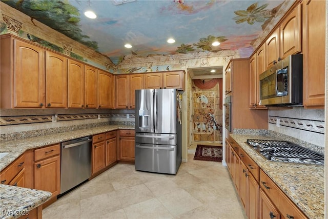 kitchen featuring light stone counters, decorative backsplash, brown cabinets, appliances with stainless steel finishes, and recessed lighting