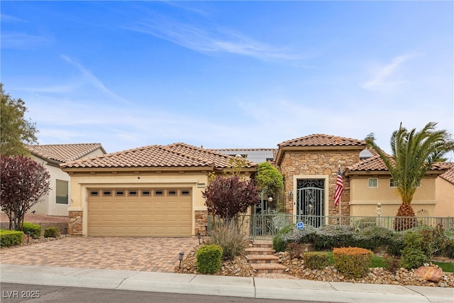 mediterranean / spanish house with a tile roof, decorative driveway, stone siding, and stucco siding