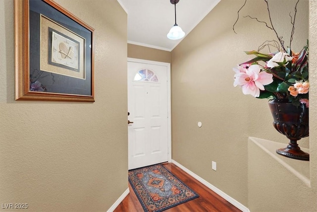 foyer entrance featuring crown molding, baseboards, and wood finished floors