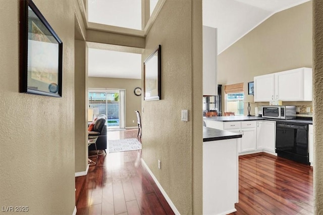 corridor featuring baseboards, dark wood-style flooring, a textured wall, and high vaulted ceiling