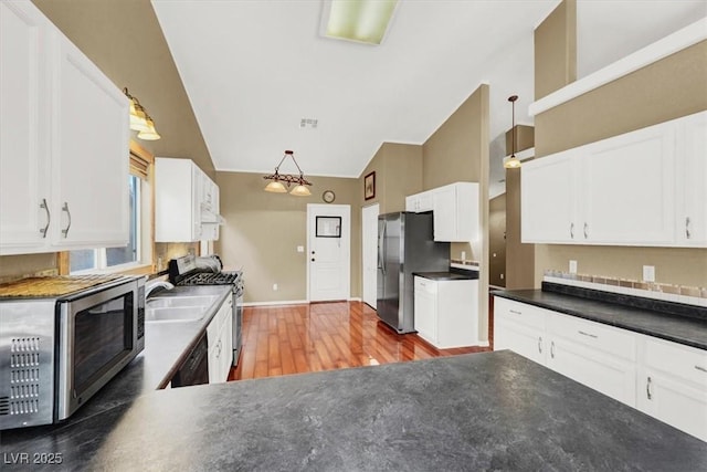 kitchen with white cabinetry, dark countertops, light wood-type flooring, and stainless steel appliances