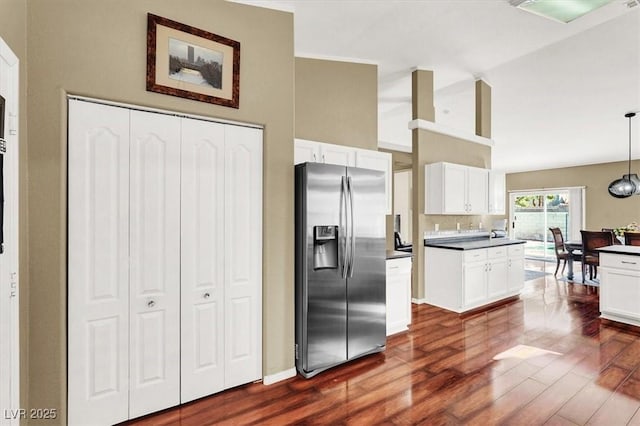 kitchen featuring dark countertops, stainless steel fridge with ice dispenser, dark wood finished floors, decorative light fixtures, and white cabinets