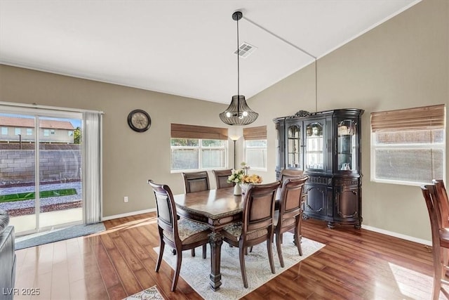 dining space featuring visible vents, lofted ceiling, baseboards, and wood finished floors