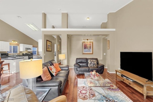 living room featuring visible vents, high vaulted ceiling, baseboards, and wood finished floors