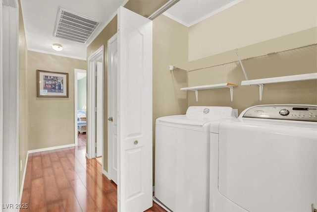 clothes washing area featuring wood finished floors, visible vents, laundry area, crown molding, and independent washer and dryer