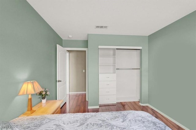 bedroom featuring wood finished floors, visible vents, a closet, and baseboards