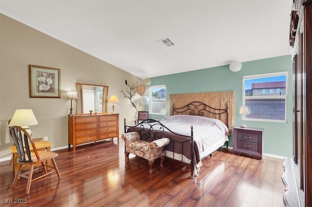 bedroom featuring visible vents, wood finished floors, baseboards, and vaulted ceiling