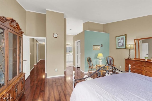 bedroom featuring baseboards, ensuite bath, wood finished floors, and ornamental molding