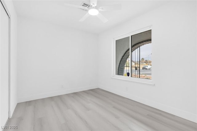 empty room with ceiling fan, visible vents, baseboards, and wood finished floors