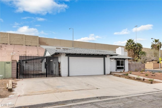 view of front facade featuring stucco siding, driveway, a gate, fence, and an attached garage