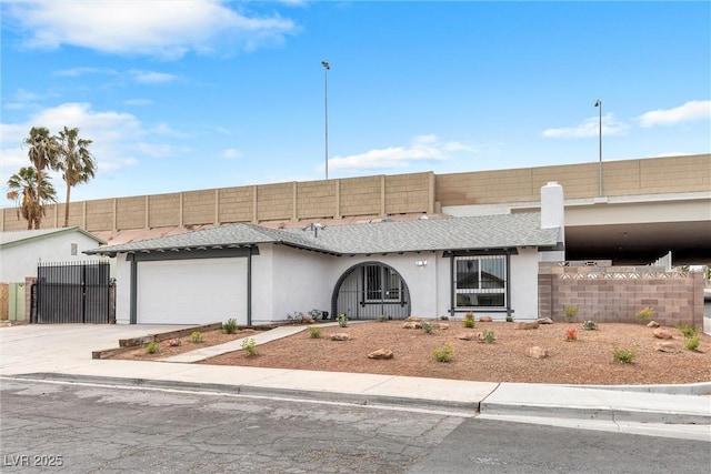 view of front of house with stucco siding, a gate, fence, concrete driveway, and a garage