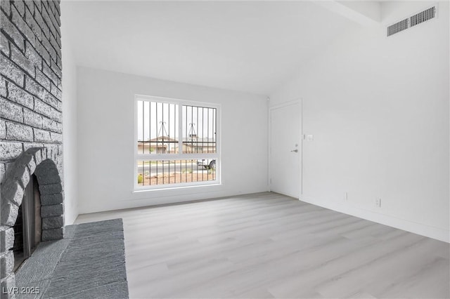 unfurnished living room featuring visible vents, a fireplace, high vaulted ceiling, and wood finished floors