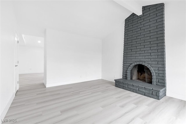 unfurnished living room with baseboards, wood finished floors, a fireplace, and vaulted ceiling with beams