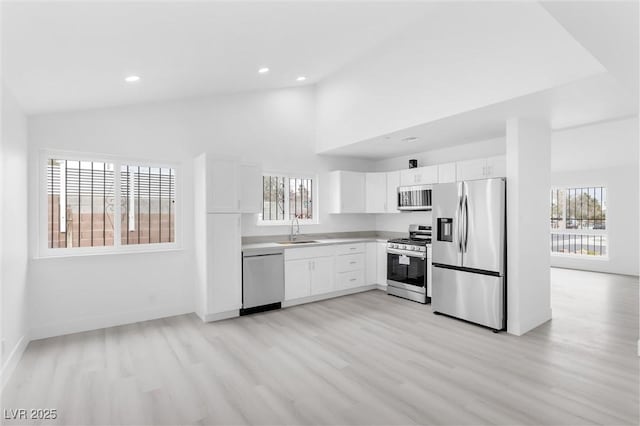 kitchen featuring recessed lighting, light wood-style flooring, appliances with stainless steel finishes, white cabinetry, and a sink