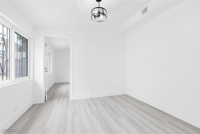 unfurnished room featuring light wood-style floors, visible vents, and baseboards