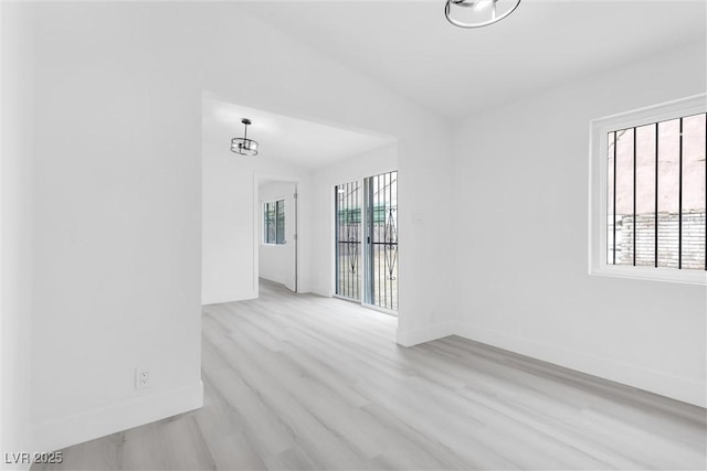 spare room featuring vaulted ceiling, baseboards, and wood finished floors