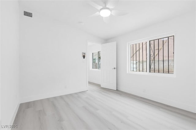 spare room with visible vents, a ceiling fan, baseboards, and wood finished floors