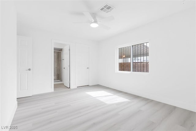 empty room featuring light wood-type flooring, visible vents, and a ceiling fan