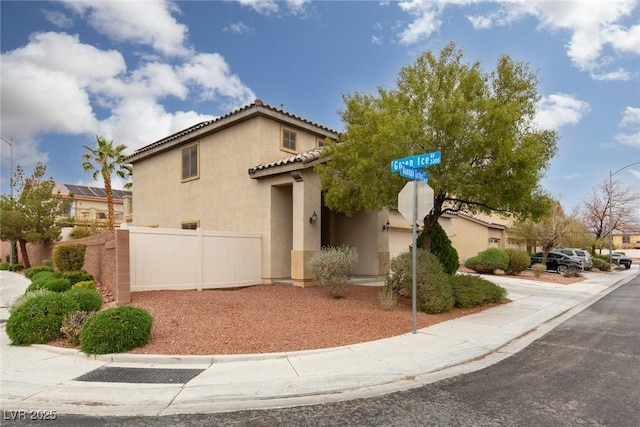 mediterranean / spanish-style house with a tiled roof, fence, a garage, and stucco siding