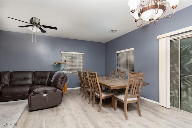 dining space featuring visible vents, ceiling fan with notable chandelier, baseboards, and wood finished floors