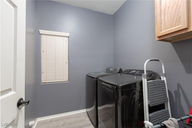 clothes washing area featuring cabinet space, washer and dryer, light wood-style flooring, and baseboards