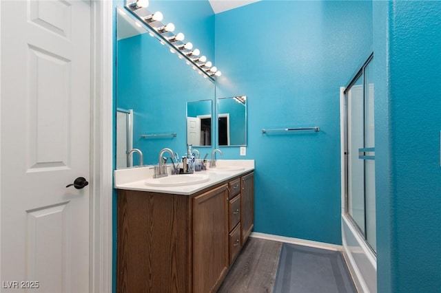 bathroom featuring double vanity, wood finished floors, baseboards, and a sink