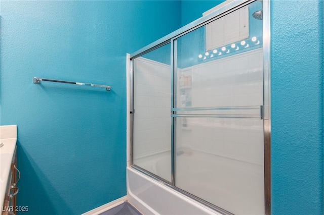 full bathroom featuring bath / shower combo with glass door and a textured wall