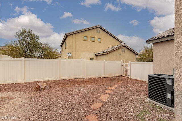 view of yard with central AC, a fenced backyard, and a gate