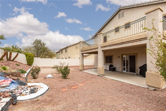 rear view of property featuring a patio area, stucco siding, and a fenced backyard