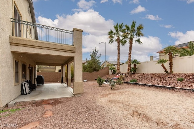 view of yard with a patio, a balcony, and a fenced backyard