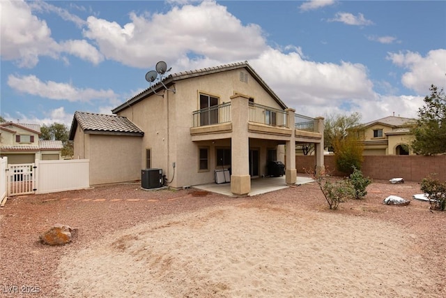 back of house featuring a balcony, a fenced backyard, stucco siding, a tiled roof, and a patio area