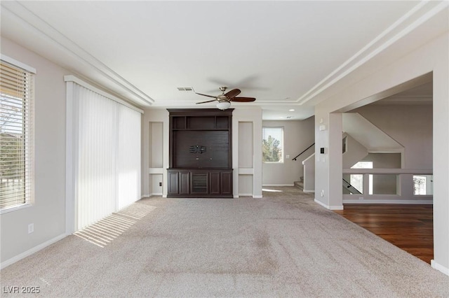 unfurnished living room with baseboards, visible vents, carpet floors, ceiling fan, and stairs