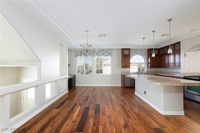 kitchen with a center island, stainless steel range with gas cooktop, an inviting chandelier, light countertops, and dark wood-style flooring