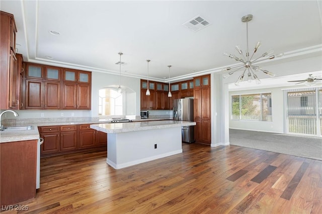 kitchen featuring visible vents, a kitchen island, stainless steel fridge with ice dispenser, light countertops, and a sink