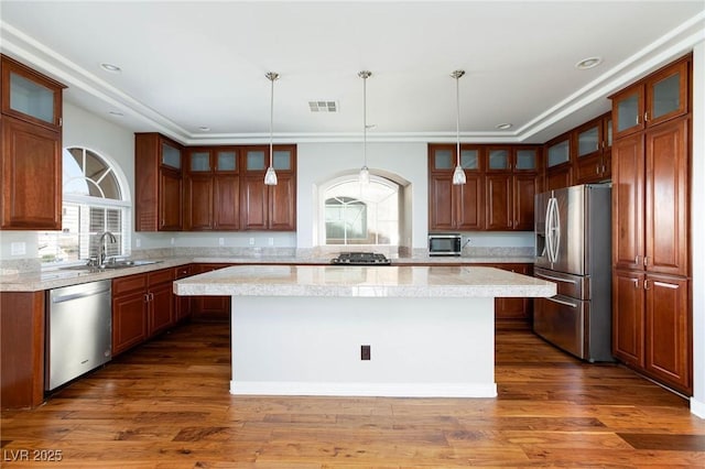 kitchen featuring visible vents, a center island, dark wood finished floors, appliances with stainless steel finishes, and a sink