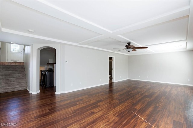 empty room featuring baseboards, ceiling fan, dark wood finished floors, stairway, and arched walkways