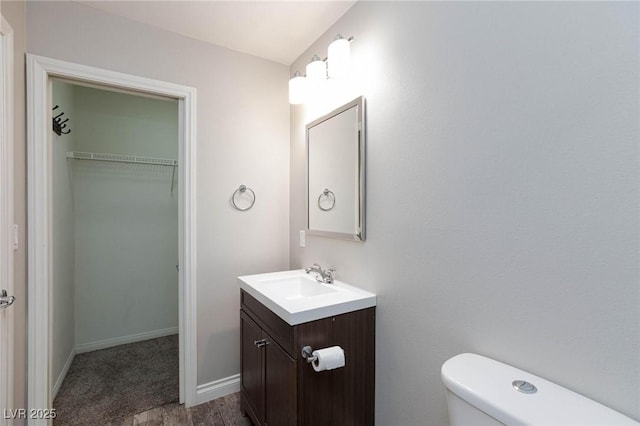 half bath featuring toilet, vanity, and baseboards