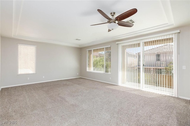 carpeted spare room featuring visible vents, ceiling fan, a raised ceiling, and baseboards