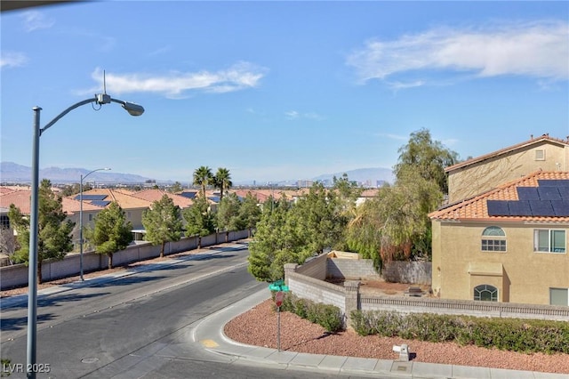 view of road with curbs, a mountain view, street lighting, and sidewalks