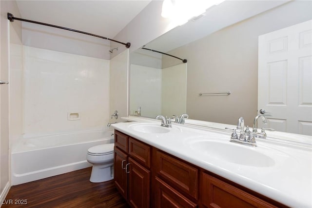 bathroom featuring wood finished floors, tub / shower combination, toilet, and a sink